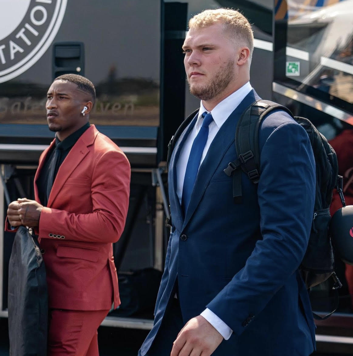 2 Sportsmen wearing a suit walking out from a bus