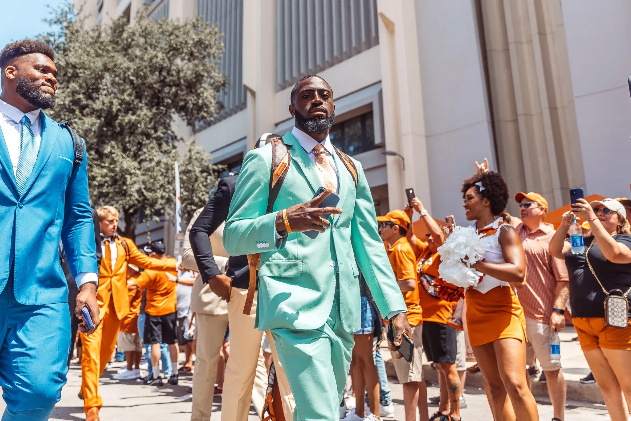 A group of sportsmen wearing different colors of suits walking in a parade